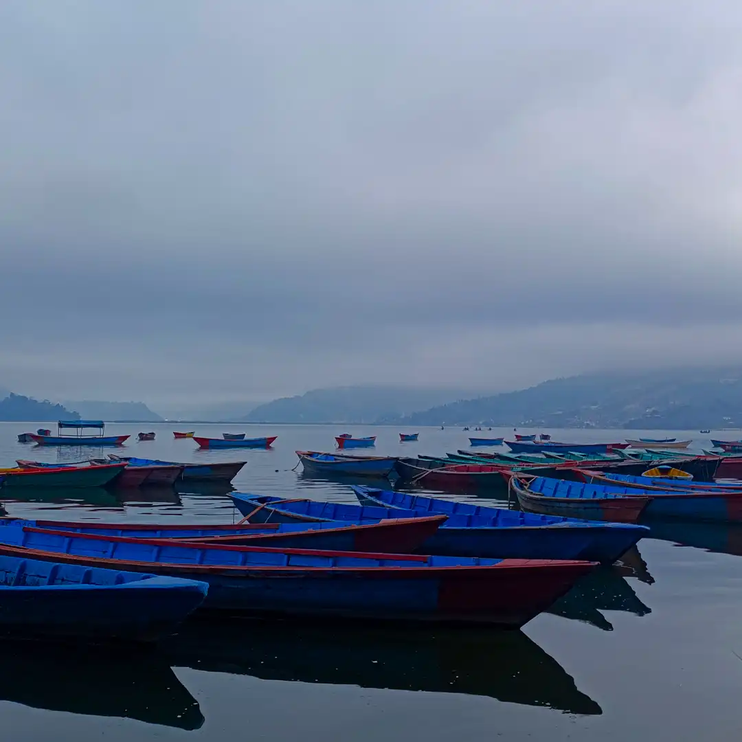 Close-up of traditional wooden boat on Fewa Lake with colorful striped roof and oars resting Pokhara Nepal